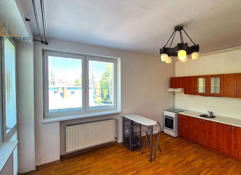 Küche in einer Einzimmerwohnung mit Platz für eine Essecke und einem Boden in Holzoptik.