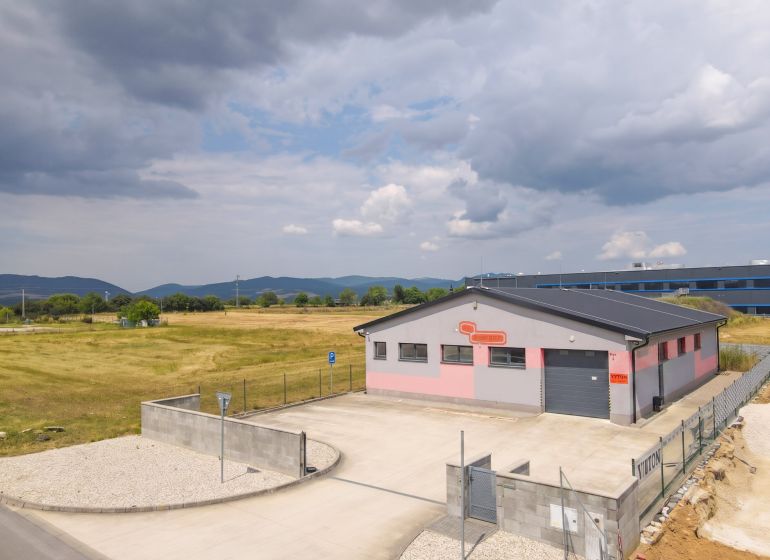 Ein Industriegebäude in Nová Dubnica, umgeben von Feldern und Bergen.
