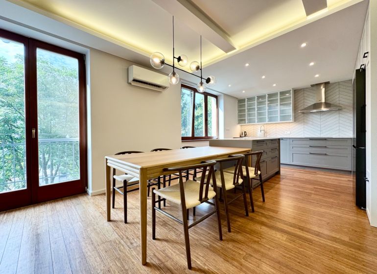 Küche in einer 3-Zimmer-Wohnung, Boden mit Holzdekor, große Fenster, Esstisch.