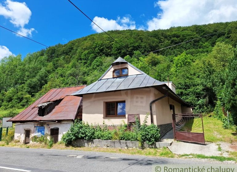 Ein älteres Haus mit Schrägdach in Mýto pod Ďumbierom, umgeben von Grün.