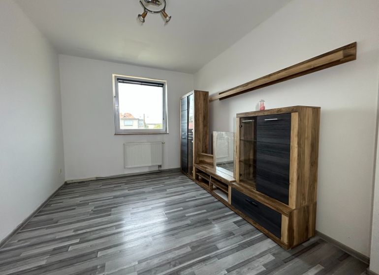 Wohnzimmer in einer 2-Zimmer-Wohnung mit Holzboden und Möbeln.
