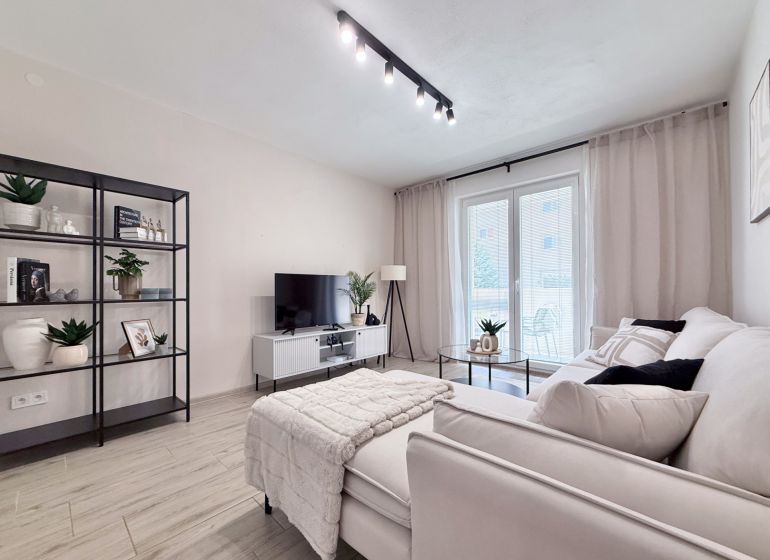 Helles Wohnzimmer in einer 2-Zimmer-Wohnung mit Regal und Sofa, Boden mit Holzdekor.