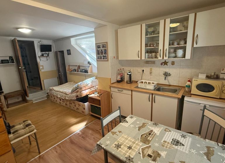 Küchenecke mit Schränken, Tisch und Sofa, Boden mit Holzdekor in einem Einfamilienhaus.