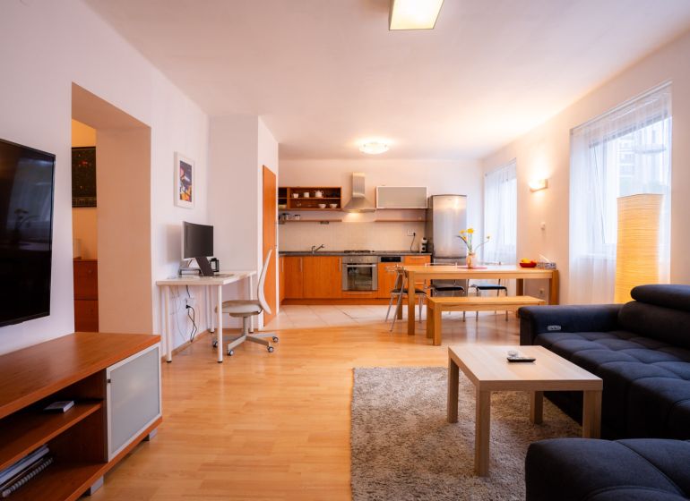 Wohnzimmer mit Küche in einer 4-Zimmer-Wohnung, mit einem Boden in Holzoptik und vielseitiger Einrichtung.