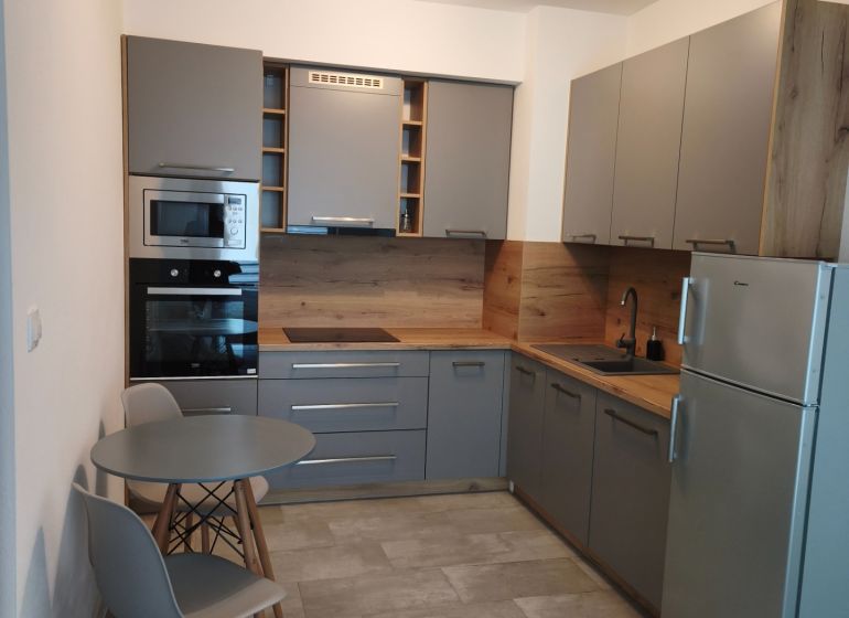 Küche in einer Einzimmerwohnung mit Essecke und grauen Schränken.