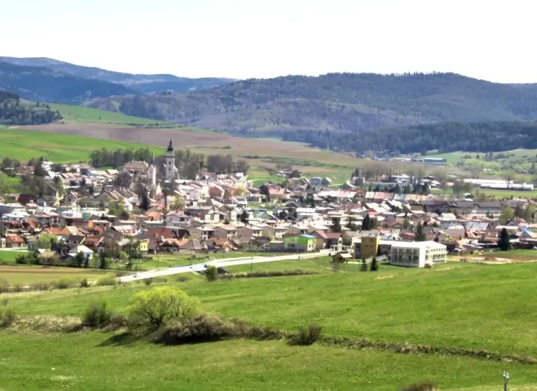 Ľubica, umgeben von landwirtschaftlichen und forstwirtschaftlichen Flächen mit Hügeln im Hintergrund.