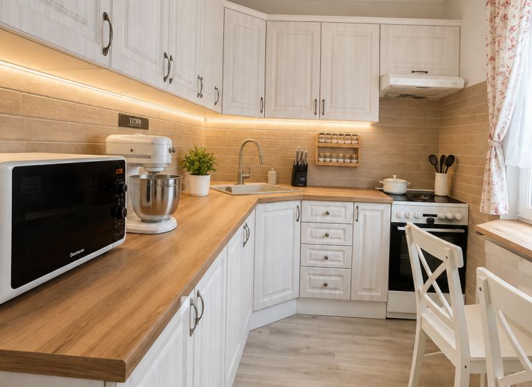 Küche in einer 3-Zimmer-Wohnung mit Holzboden und weißen Möbeln.