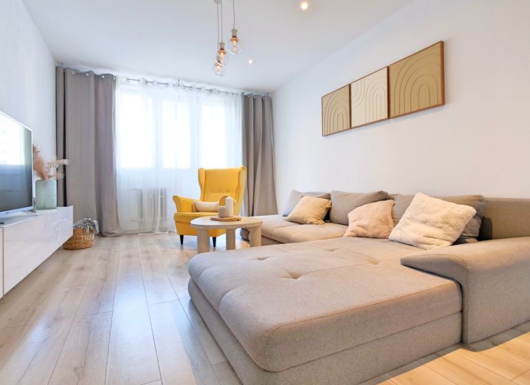 Wohnzimmer in einer 2-Zimmer-Wohnung mit Holzboden und bequemen Sitzgelegenheiten.