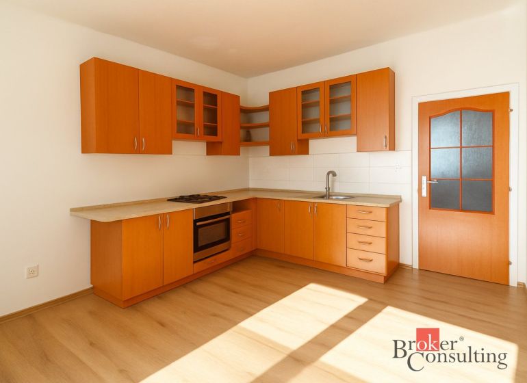 Küche in einer 2-Zimmer-Wohnung mit Holzschränken und einem Boden in Holzoptik.