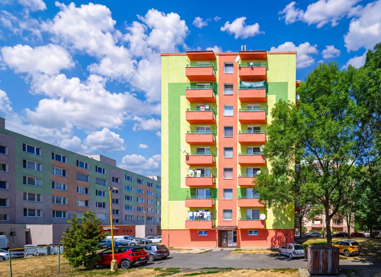 Bunte Wohnhäuser in der Sládkovičova-Straße in Fiľakovo mit Parkplatz und Grünflächen.