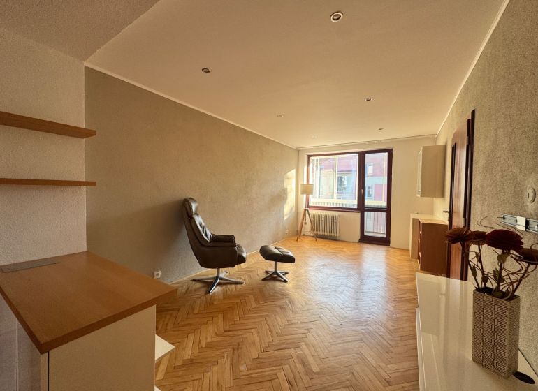 Wohnzimmer in einer Vierzimmerwohnung mit Holzboden und einem bequemen Sessel.