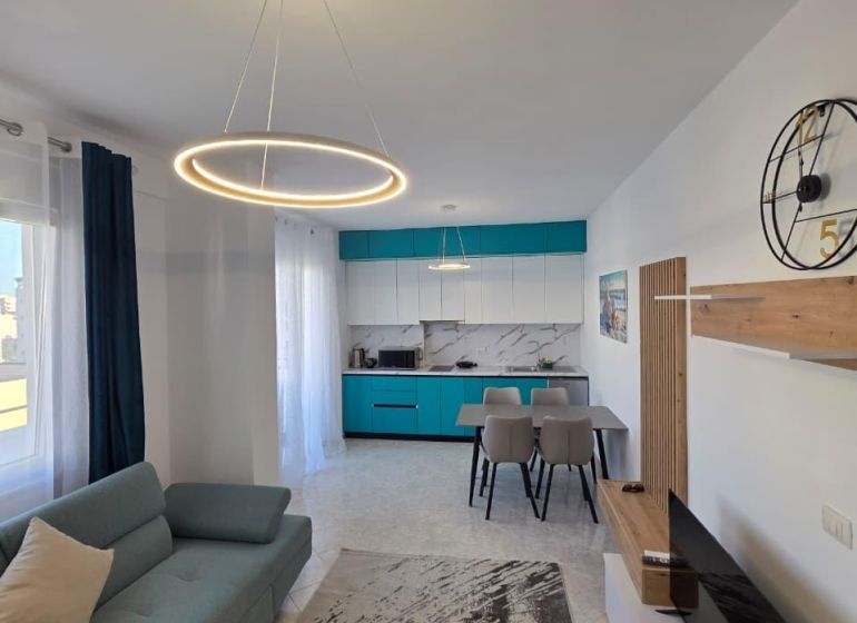 Wohnzimmer einer 2-Zimmer-Wohnung mit stilvoller Beleuchtung, Küche und bequemer Couch.
