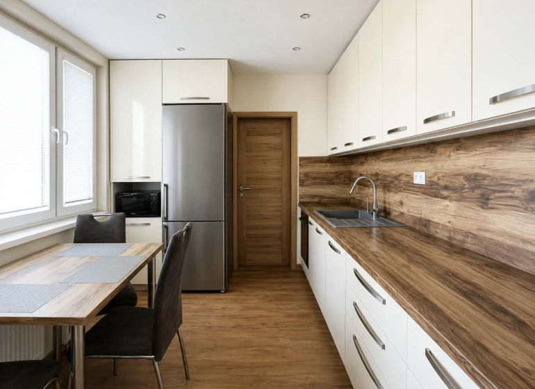 Küche in einer 3-Zimmer-Wohnung mit Boden und Arbeitsplatte in Holzoptik.