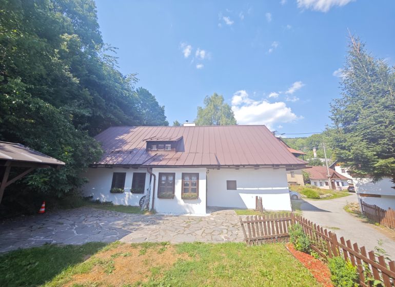 Eine Hütte in Špania Dolina, umgeben von Natur, mit einem steinernen Weg und einem Holzzaun.