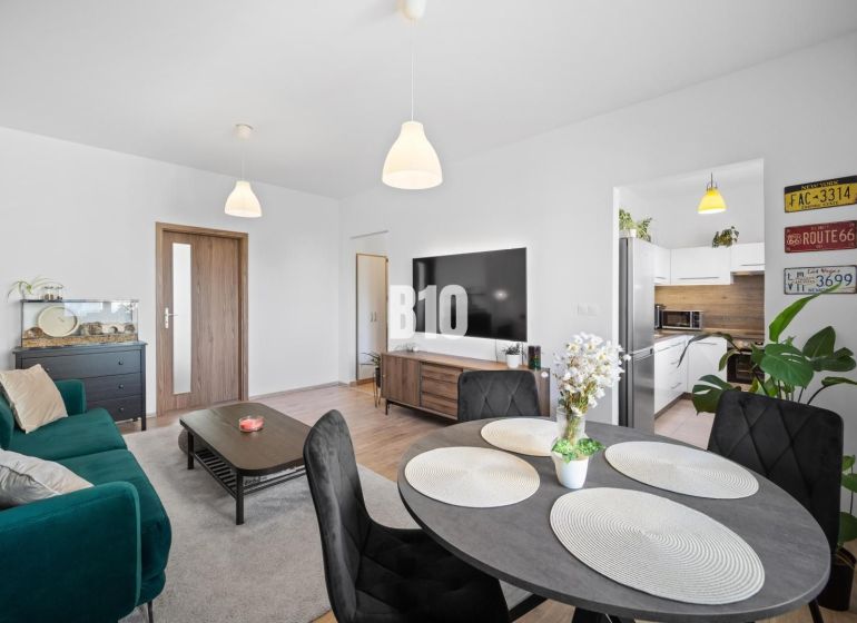Wohnzimmer in einer Zweizimmerwohnung mit Holzboden und Esstisch.
