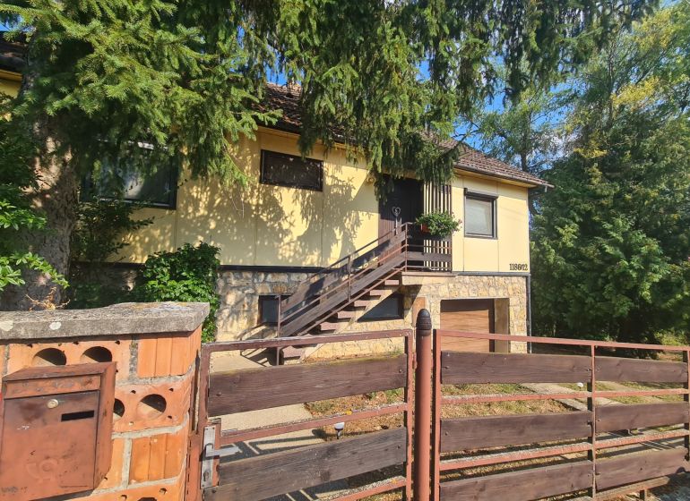 Ein Einfamilienhaus in Svodín mit Treppe, Umzäunung und dichter Vegetation rundherum.