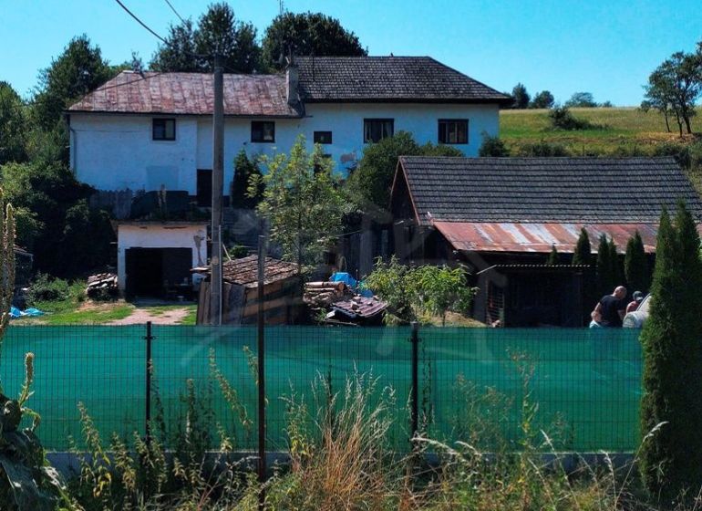 Ein Einfamilienhaus in Stará Turá mit Garten, Umzäunung und Anbauten, mit Blick auf die Landschaft.
