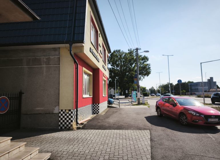 Geschäftsräume in der Straße SNP in Šaľa mit einem roten Auto auf der Straße.