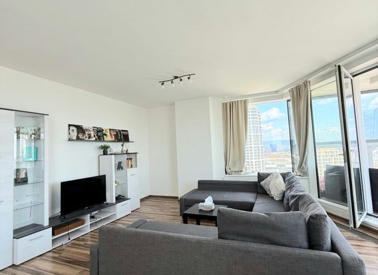 Wohnzimmer mit Holzboden, Sofa und Fernseher in einer 3-Zimmer-Wohnung.
