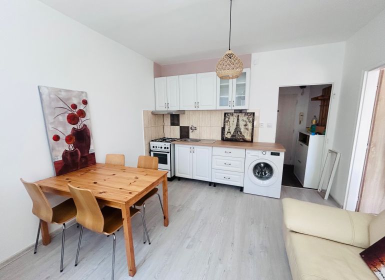 Küche in einer Einzimmerwohnung mit Holztisch, Stühlen und Boden mit Holzdekor.