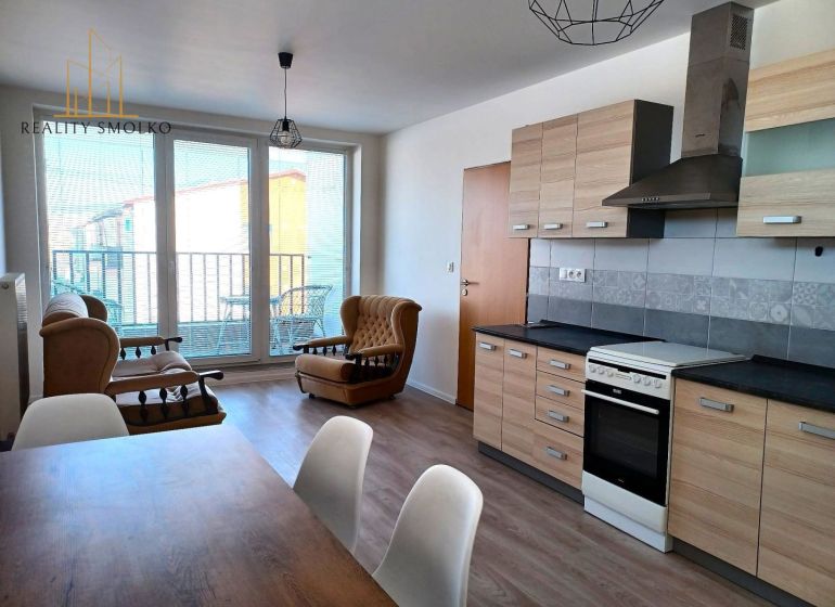 Wohnzimmer mit Sofas, Küchenzeile und Holzboden in einer Zweizimmerwohnung.