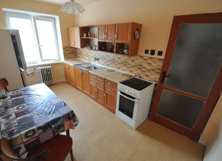 Küche einer 2-Zimmer-Wohnung mit Esstisch, Küchenzeile und Elektroherd.