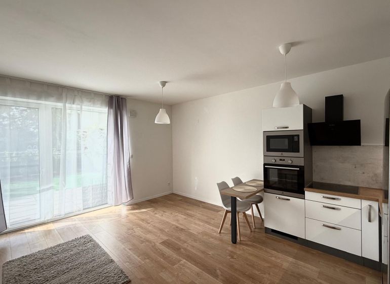 Küche in einer 2-Zimmer-Wohnung mit Holzboden und eingebauten Geräten.