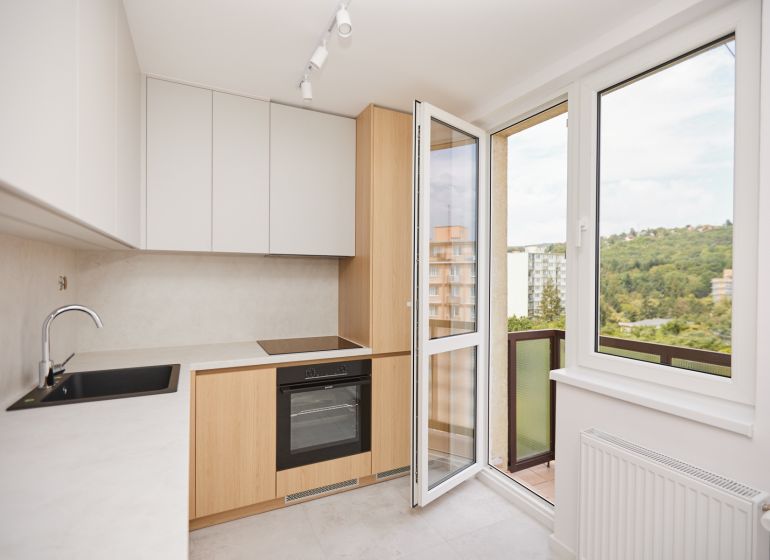 Küche in einer 3-Zimmer-Wohnung mit Blick vom Balkon und einem Boden mit Holzdekor.