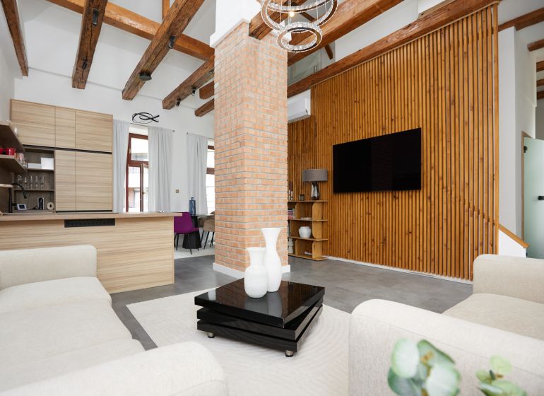 Wohnzimmer mit Ziegelwand, Holzboden und bequemen Sesseln in einer 3-Zimmer-Wohnung.