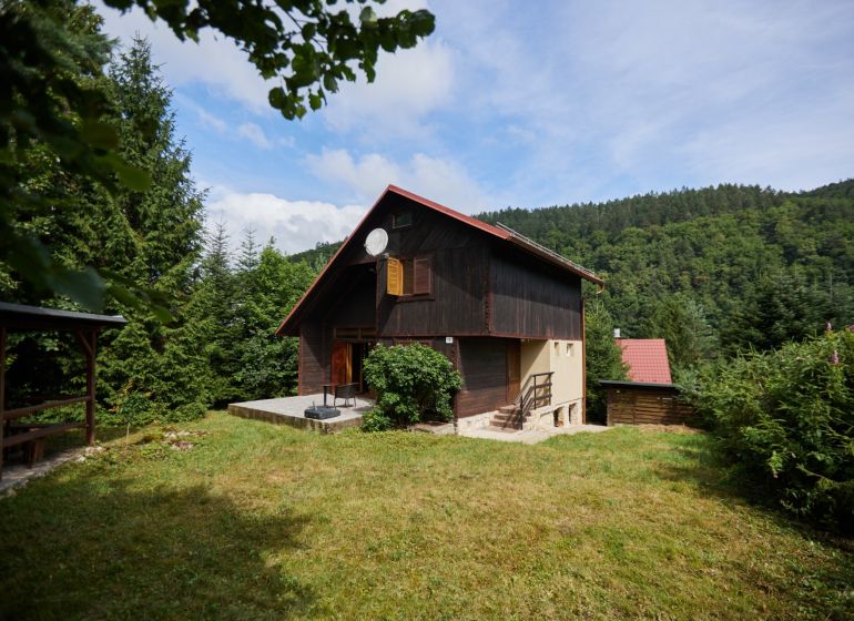 Das Haus in der Straße Rovné 61, Jaklovce, umgeben von Grün und Wald, mit einer Außensitzgelegenheit.