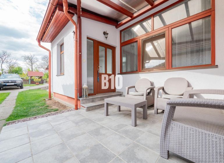 Einfamilienhaus in Nitra mit einem Gartenbereich auf einer gepflasterten Terrasse, Raum für Entspannung.