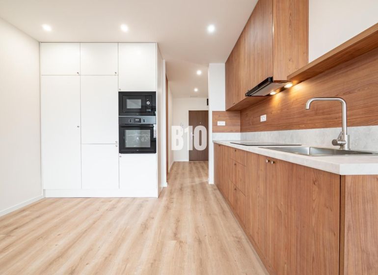 Küche in einer 3-Zimmer-Wohnung mit weißen Schränken und einem Boden in Holzoptik.