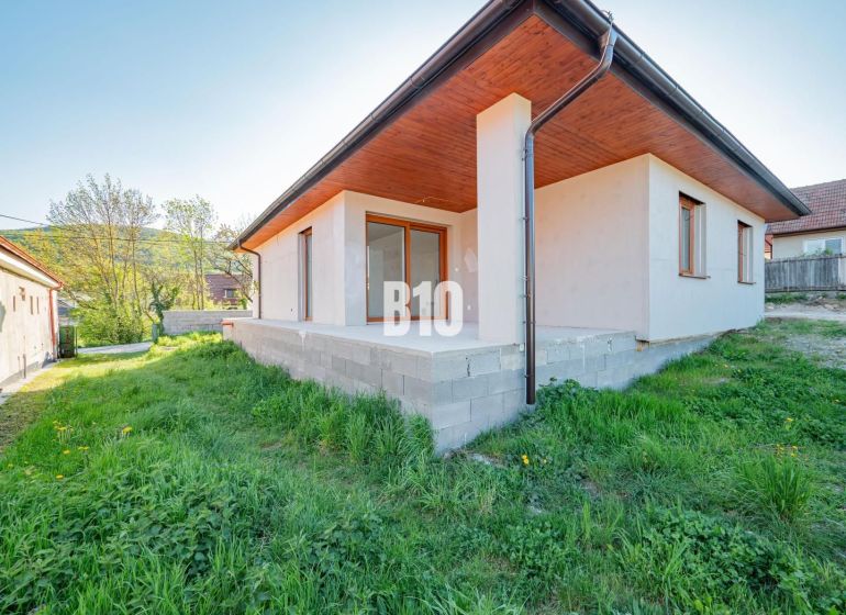 Ein Einfamilienhaus in Nitra mit einer Betonterrasse und einem grünen Rasen im Garten.