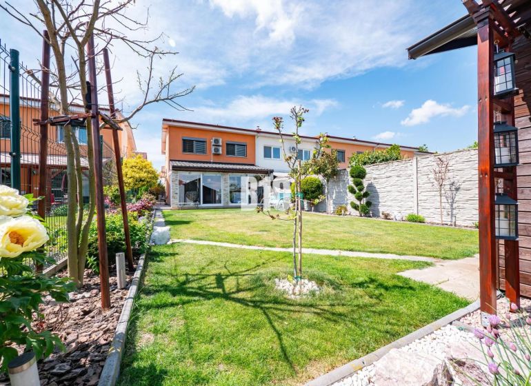 Ein Garten bei einem Einfamilienhaus in Nitra mit Rasen, Blumen und Terrasse.