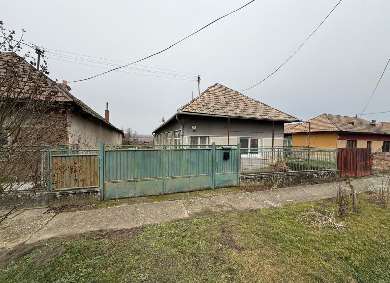 Ein Einfamilienhaus in Sikenica mit einem älteren Zaun und Garten, umgeben von weiteren Häusern.