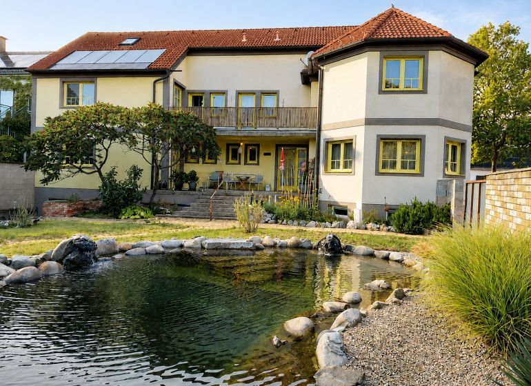 Einfamilienhaus in Podersdorf am See mit großem Garten, Teich und Solarpanelen.