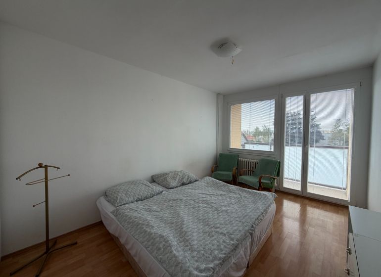 Schlafzimmer in einer 3-Zimmer-Wohnung mit Holzboden, Bett und Sesseln.