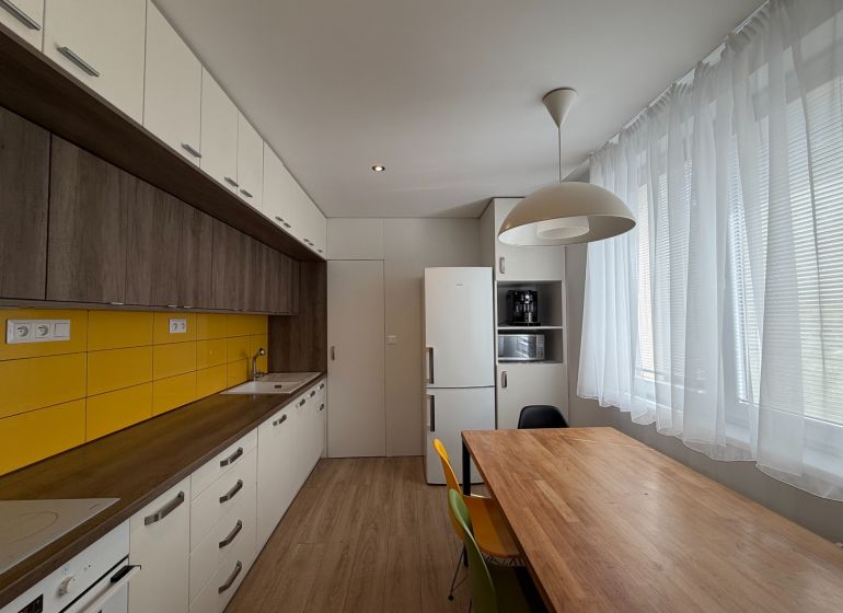 Eine Küche mit Holzboden, gelben Fliesen und einem Esstisch in einer 3-Zimmer-Wohnung.