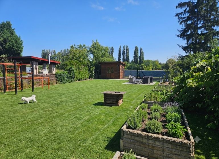 Garten in Kamenný Mlyn, Trnava mit grünem Rasen und Hochbeeten.