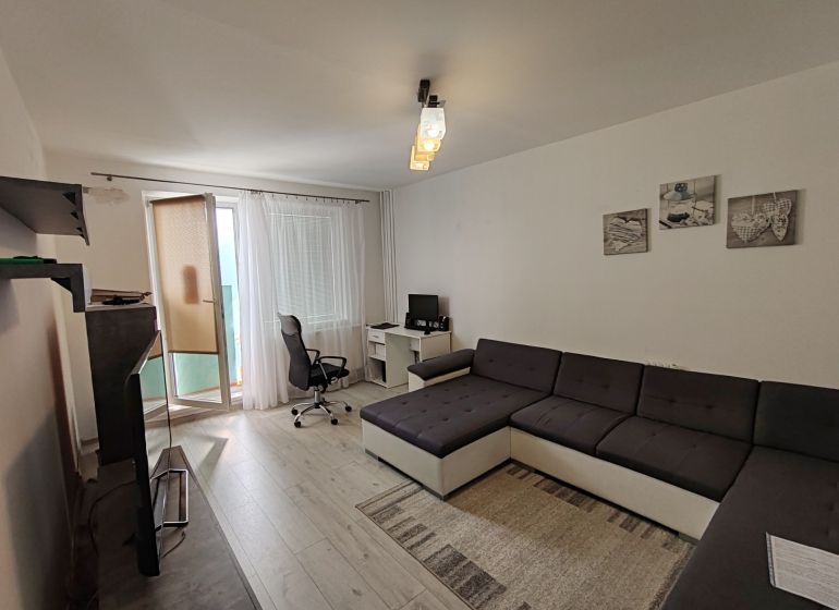 Wohnzimmer in einer 3-Zimmer-Wohnung mit Holzboden, Arbeitsbereich und Sofa.