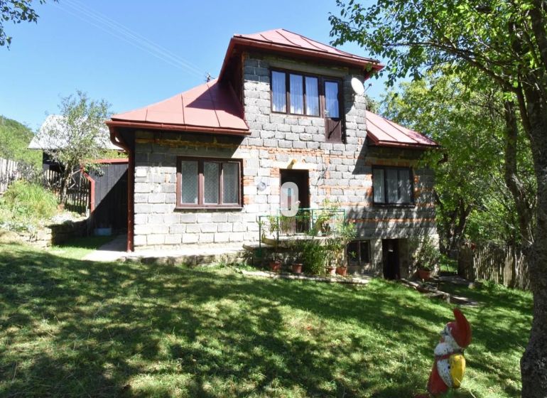 Ein Einfamilienhaus in Dlhé Pole mit einer Ziegelfassade, umgeben von Grün und Gartendekorationen.