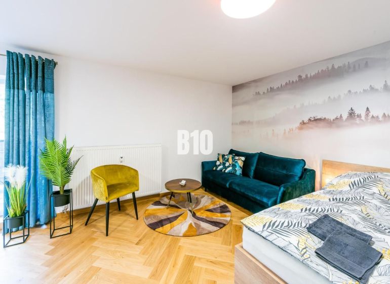 Stilvolles Ferienapartment mit Holzboden, Sofa und Pflanzen.