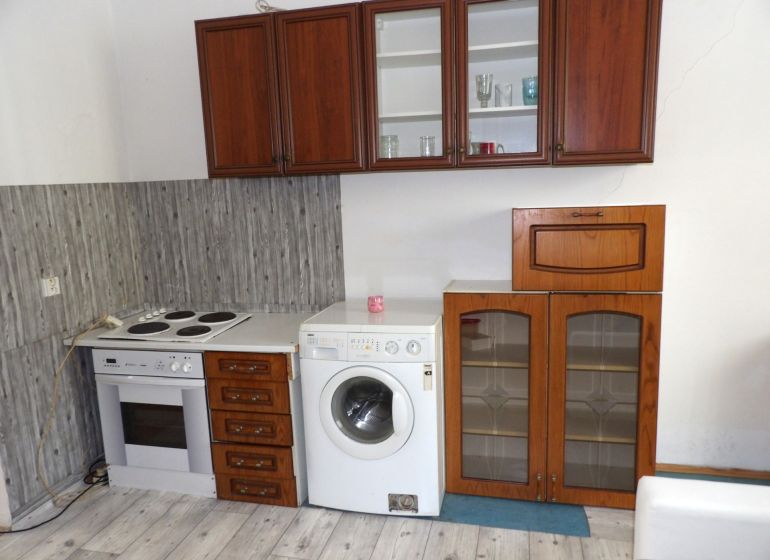 Küche in einer 2-Zimmer-Wohnung mit Elektroherd, Waschmaschine und Boden in Holzoptik.