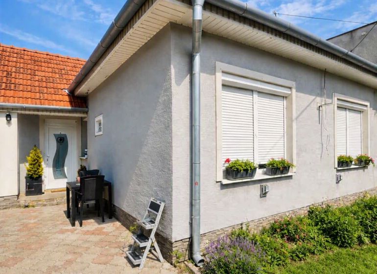 Ein Einfamilienhaus in Selice mit Blumen an den Fenstern und einem gepflasterten Hof.