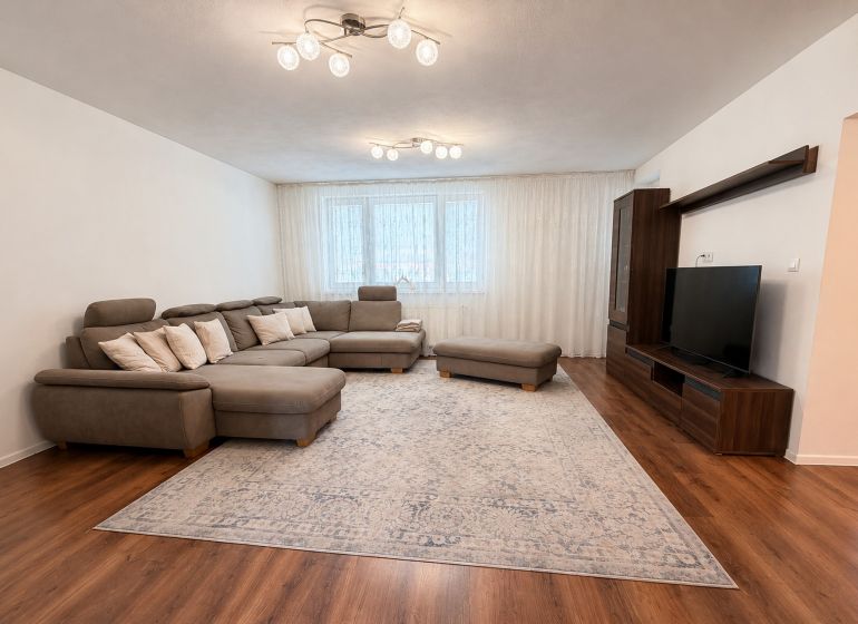 Wohnzimmer mit großem Sofa, Fernseher und Holzboden in einem Einfamilienhaus.