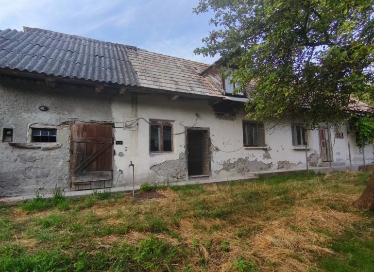 Ein Einfamilienhaus in Čelovce mit abgenutztem Putz, Holztüren und einem Garten.