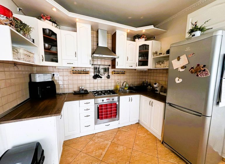 Küche in einem Einfamilienhaus mit weißen Schränken und einem Kühlschrank aus Edelstahl.