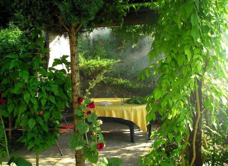 Gartenmöbel bei der Hütte in Žilina, umgeben von Grün und Blumen.