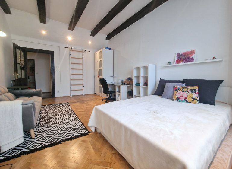 Ein Zimmer mit einem Bett, einem Sofa und einem Boden mit Holzdekor in einer 3-Zimmer-Wohnung.