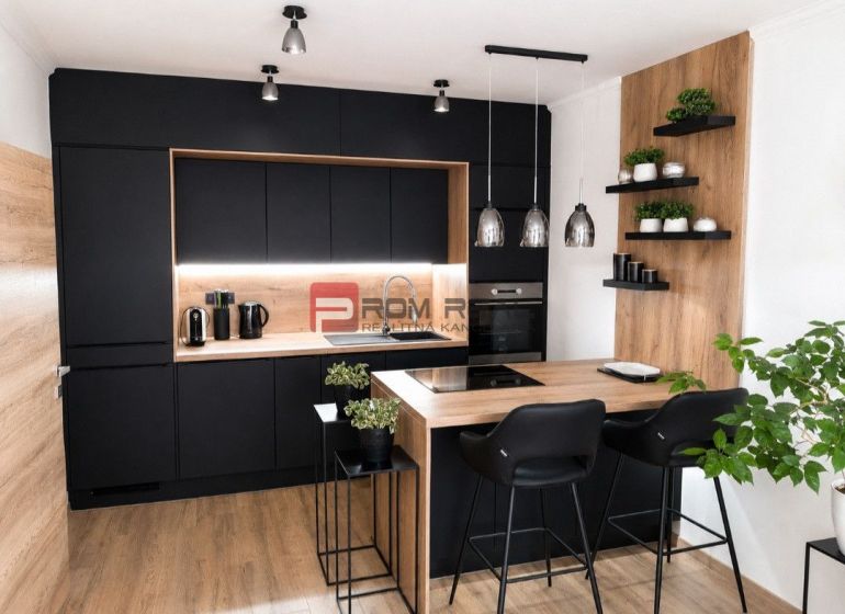 Stilvolle Küche mit schwarzen Schränken und Holzboden in einer 2-Zimmer-Wohnung.
